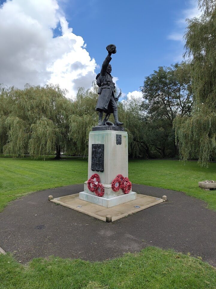 War memorial with a lone solider smiling and raising an arm with helmet